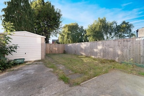A backyard with a shed, a wooden fence, and a paved driveway. - Darlington Central 4BR With Parking and Free Wifi (Darlington)