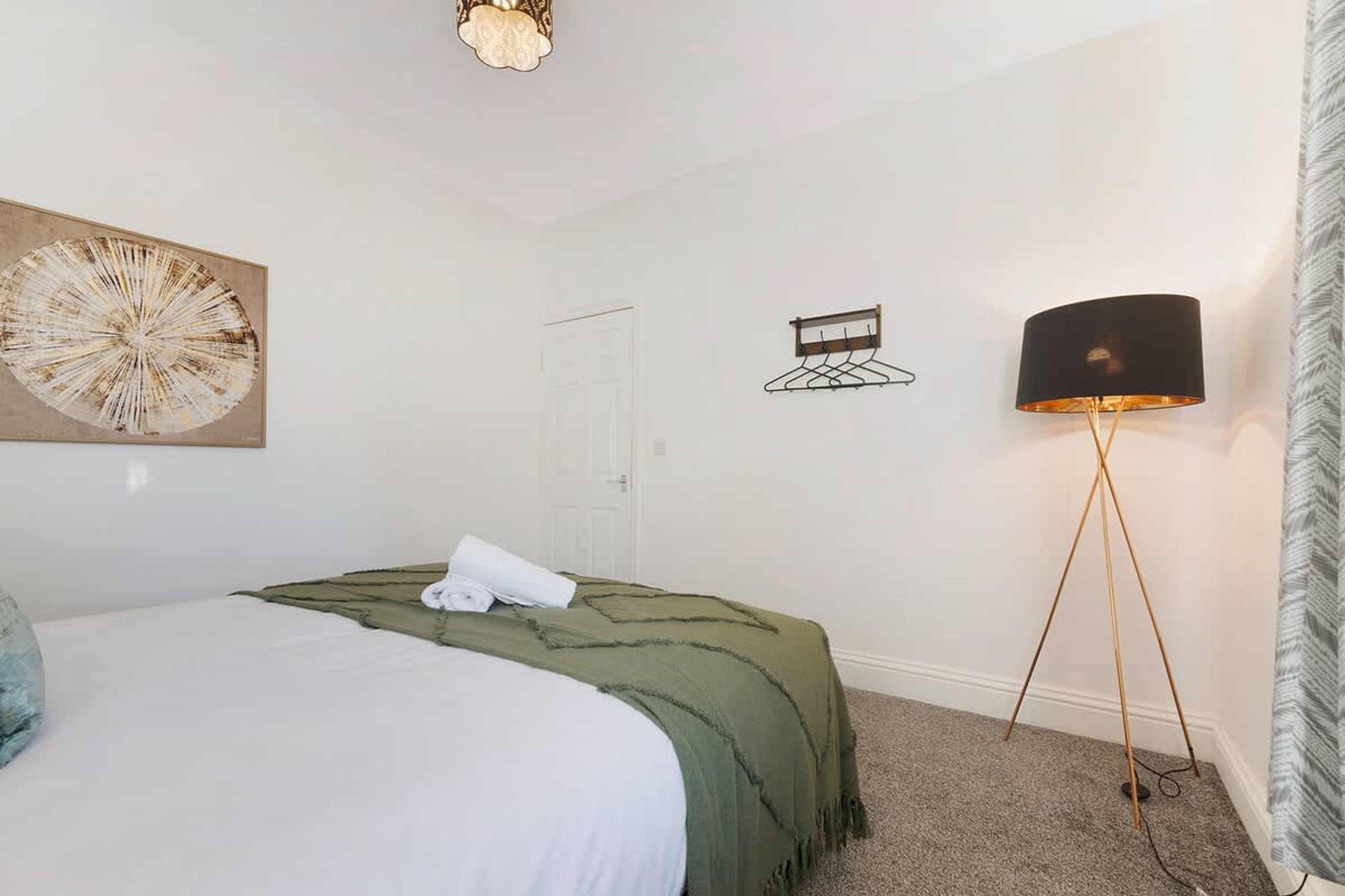 Une chambre à coucher avec un lit, une lampe fixée au mur et une porte.