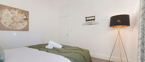 A bedroom with a bed, a wall-mounted lamp, and a door.