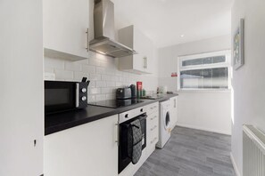 A compact kitchen with a microwave, kettle, and a built-in oven. - Darlington Central 4BR With Parking and Free Wifi (Darlington)