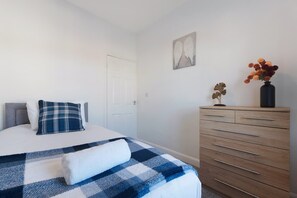 Ein Schlafzimmer mit einem Bett, einem Schminktisch und einem an der Wand hängenden Kunstwerk.