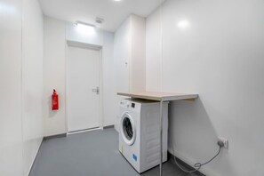 Ein Waschraum mit Waschmaschine, Feuerlöscher und einer Tür.