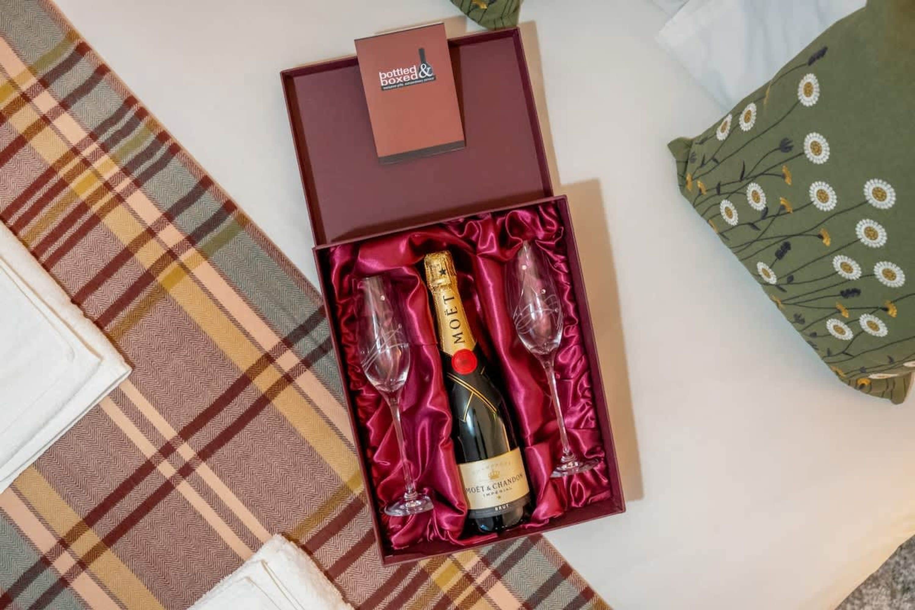 Een fles Moët & Chandon champagne in een doos met twee glazen en een rode satijnen binnenvoering.