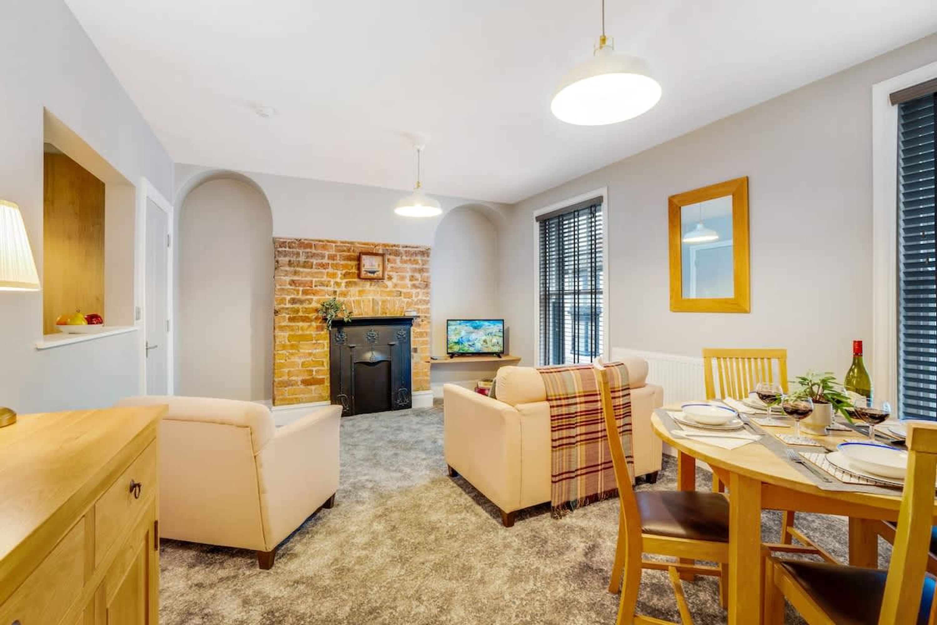 A cozy living room with a fireplace, a television, and a dining area with a table set for two.