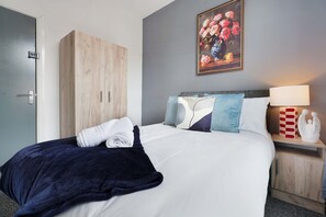 Ein Hotelzimmer mit einem Bett, einem Kleiderschrank, einem Bild an der Wand und einem Nachttisch mit Lampe und Dekoration.