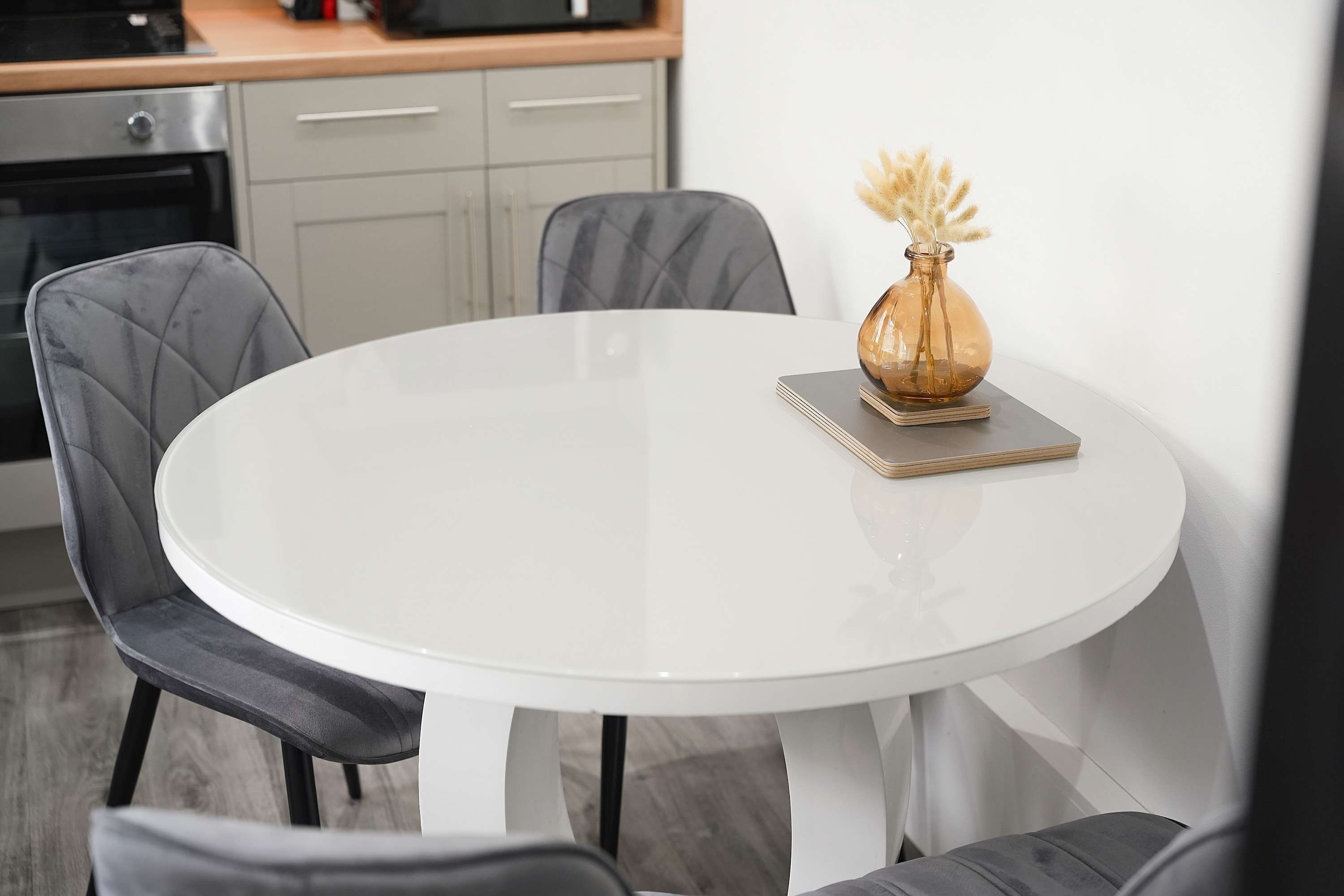 Mesa redonda blanca con un florero y una libreta.