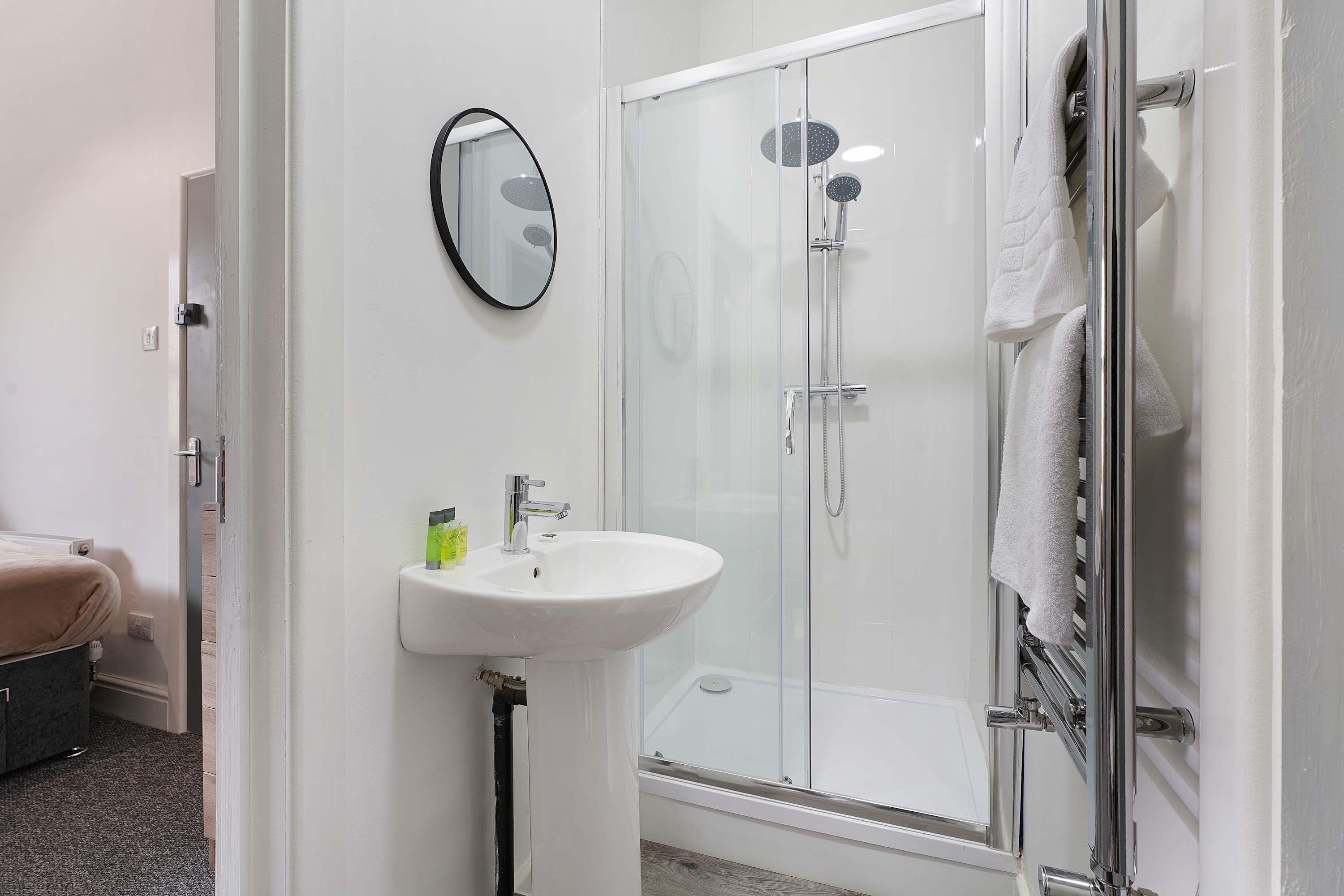 A bathroom with a shower, a sink, and a mirror.
