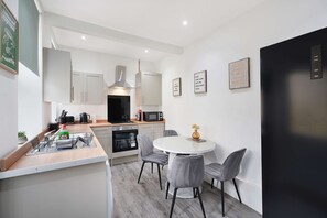 Een moderne keuken met een centraal eiland, een eettafel met stoelen en een zwarte koelkast.