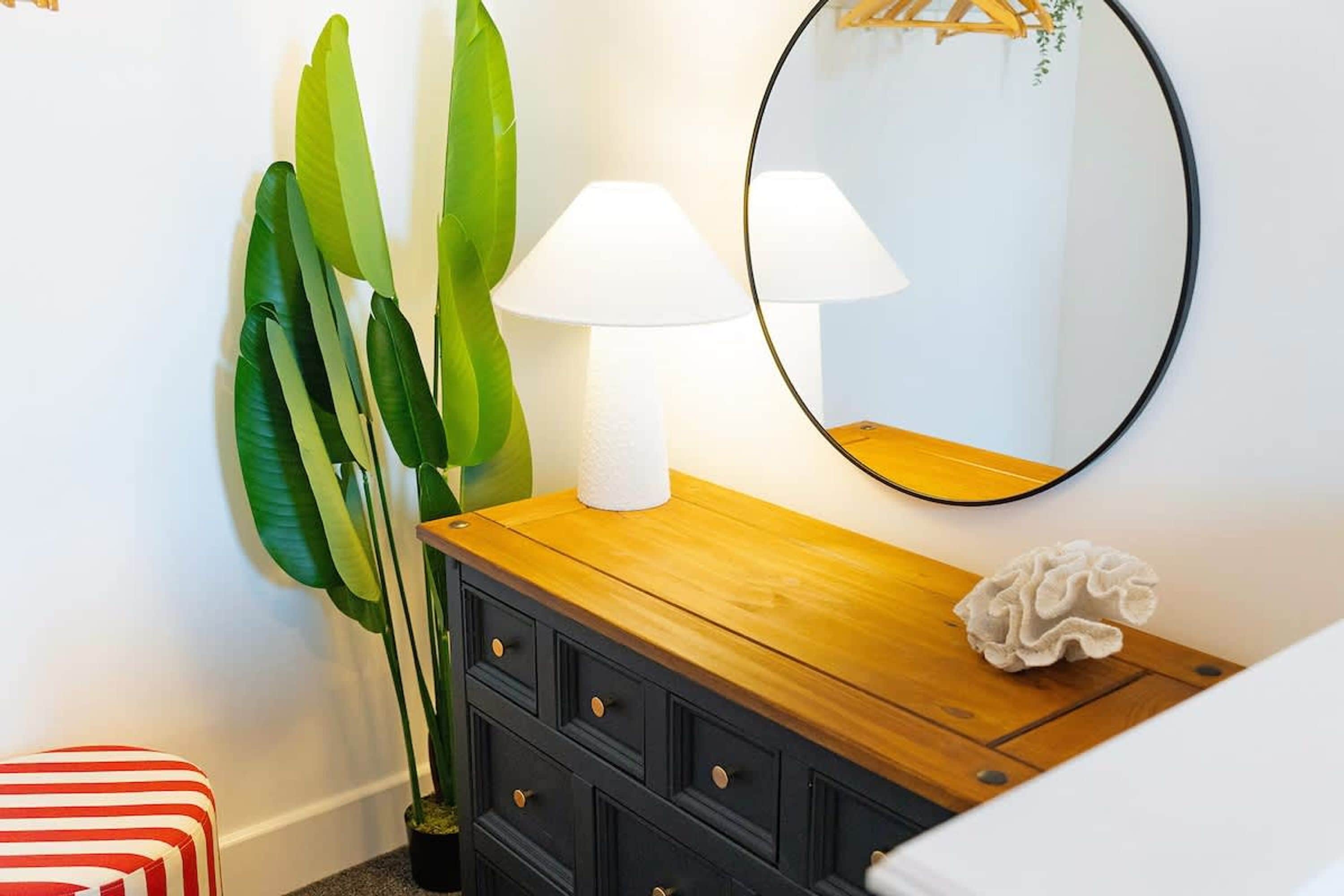 Een kamer met een houten dressoir, een spiegel en een lamp.