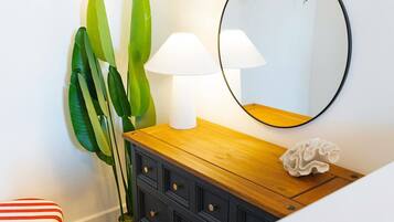 Een kamer met een houten dressoir, een spiegel en een lamp.