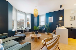 Ein modernes Wohnzimmer mit einer Couch, Sesseln, einem Couchtisch und einem Fernseher.