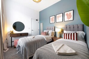 Ein Hotelzimmer mit zwei Betten, einem runden Spiegel, einem Schreibtisch und einer Wand mit drei Bildern in Rahmen.