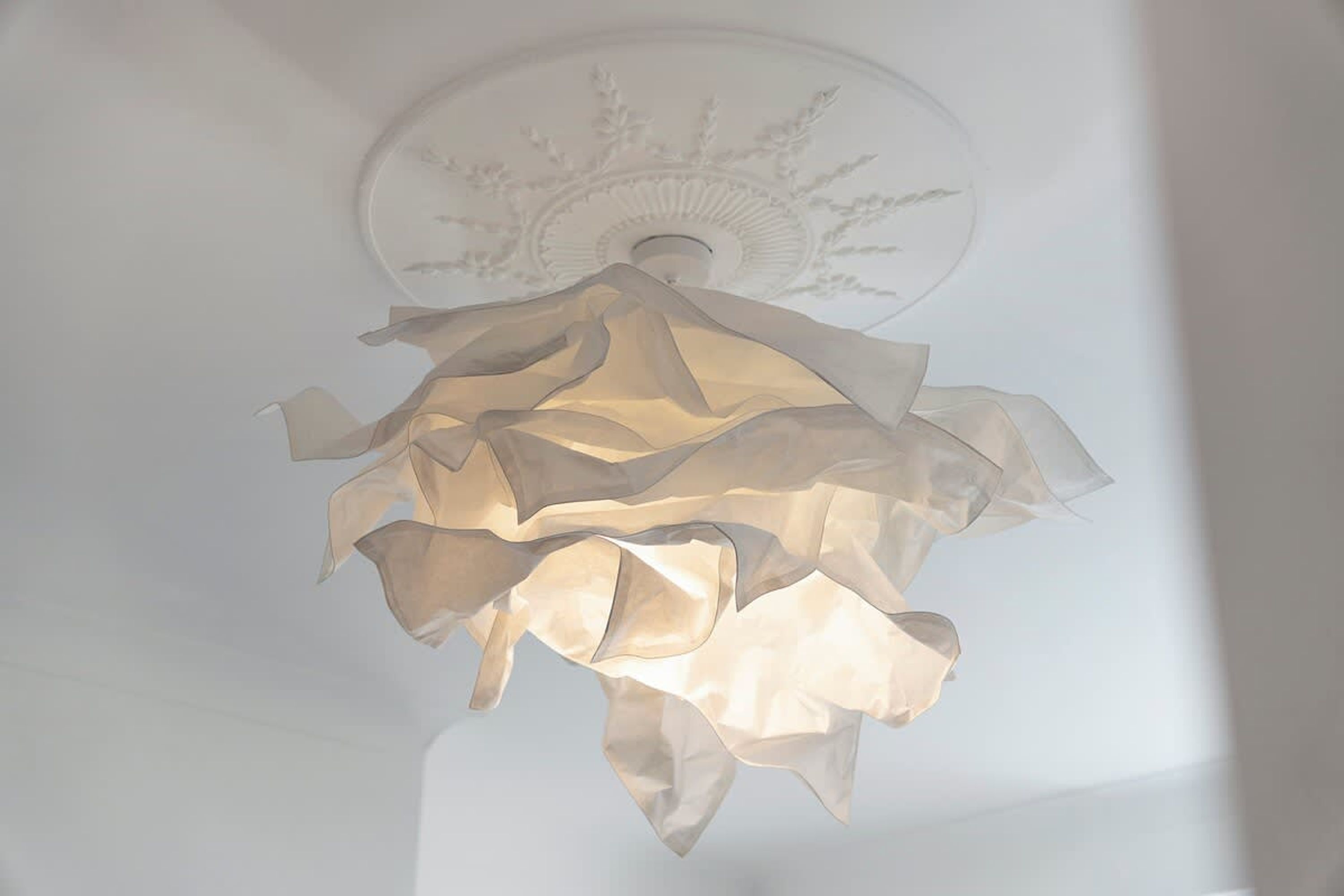 A ceiling with a decorative, layered, translucent light fixture.