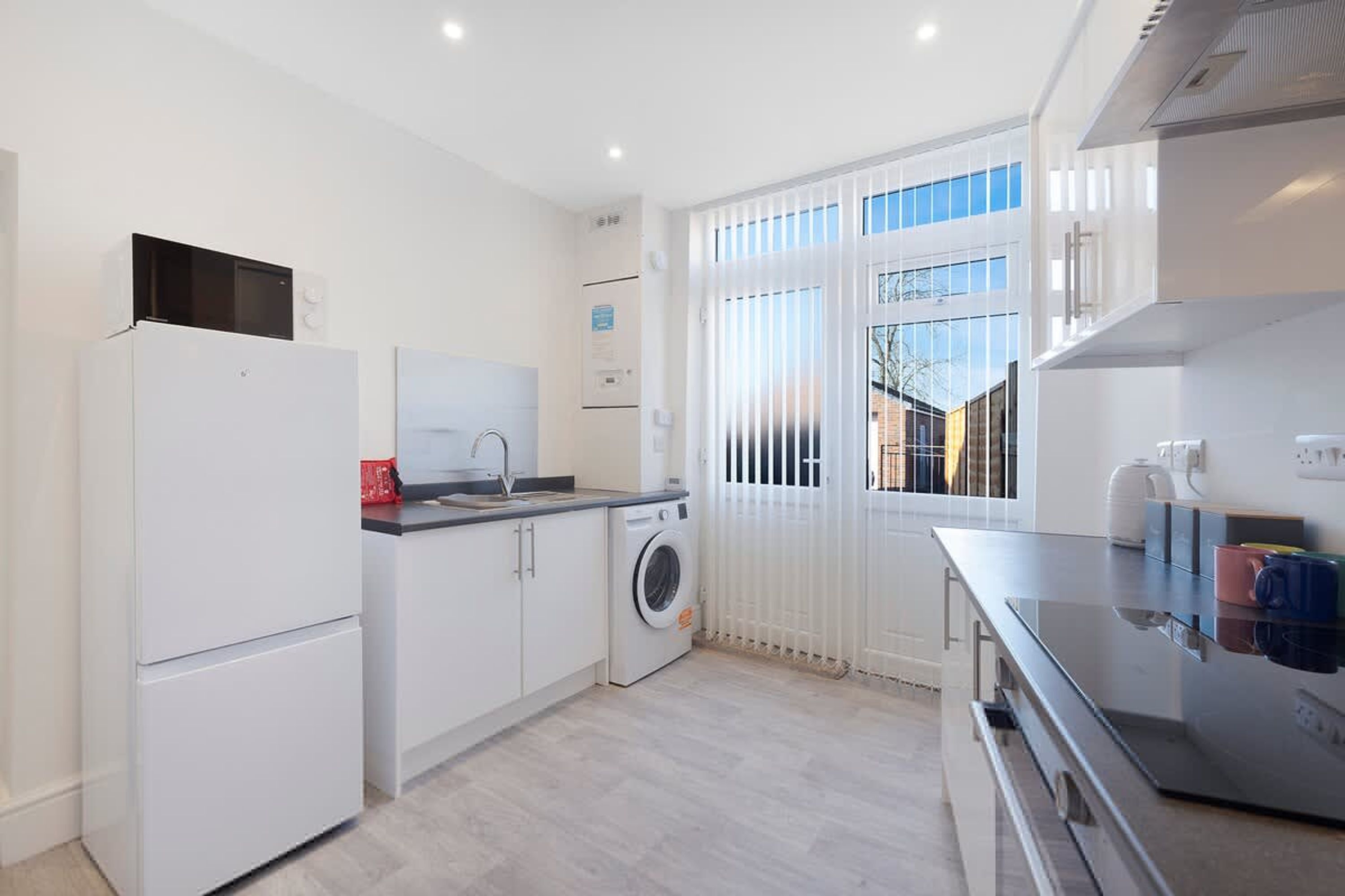 A compact kitchen with a washing machine, a refrigerator, and a microwave.