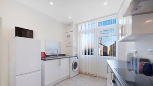 A compact kitchen with a washing machine, a refrigerator, and a microwave. - Spacious Retreat at Durham Road (Spennymoor)