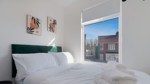 A bedroom with a bed, pillows, a green headboard, and two wall art pieces. - Spacious Retreat at Durham Road (Spennymoor)