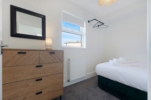 Ein Schlafzimmer mit einem Holzkapuzen, einem Bett mit weißer Bettwäsche, einem Fenster mit Ausblick und einer Heizung.