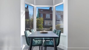 A corner room with a bay window, a dining table with chairs, and a view of neighboring houses. - Spacious Retreat at Durham Road (Spennymoor)