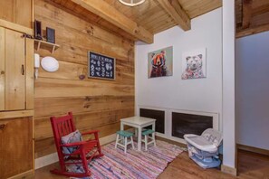 A cozy room with wooden walls, a fireplace, a rocking chair, a small table, and a colorful rug. - Bears on Beach Front * 3 beds * 2 bath * sleeps 9 (Sevierville)