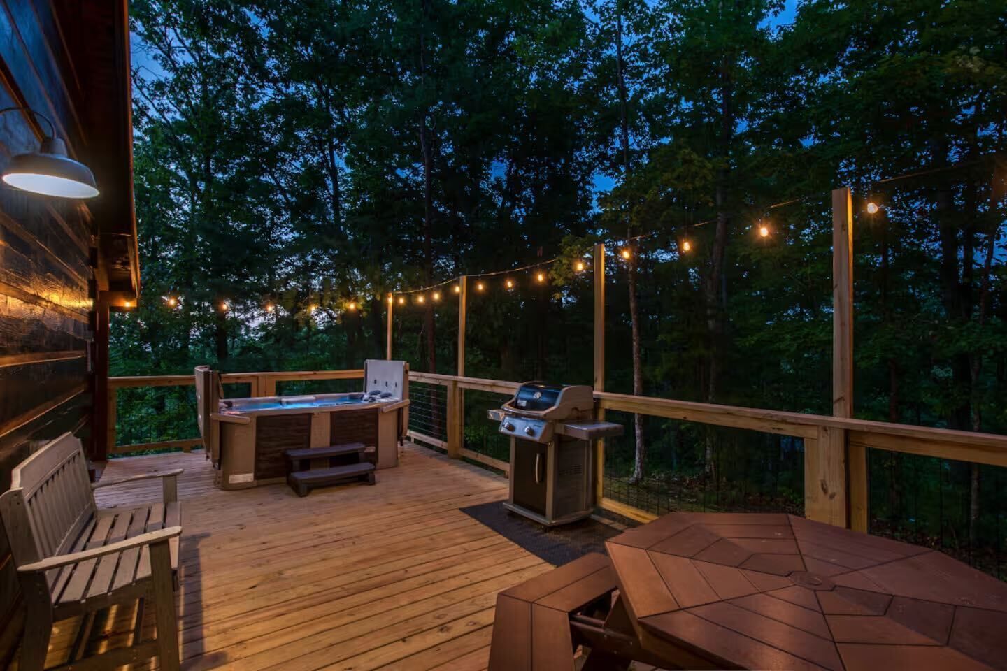 Eine Terrassenausstattung im Freien mit Whirlpool, Grill und Sitzgelegenheiten, umgeben von Bäumen.