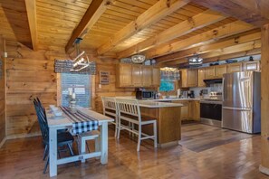 A wooden cabin interior with a dining area, kitchen, and a sign on the wall. - Bears on Beach Front * 3 beds * 2 bath * sleeps 9 (Sevierville)