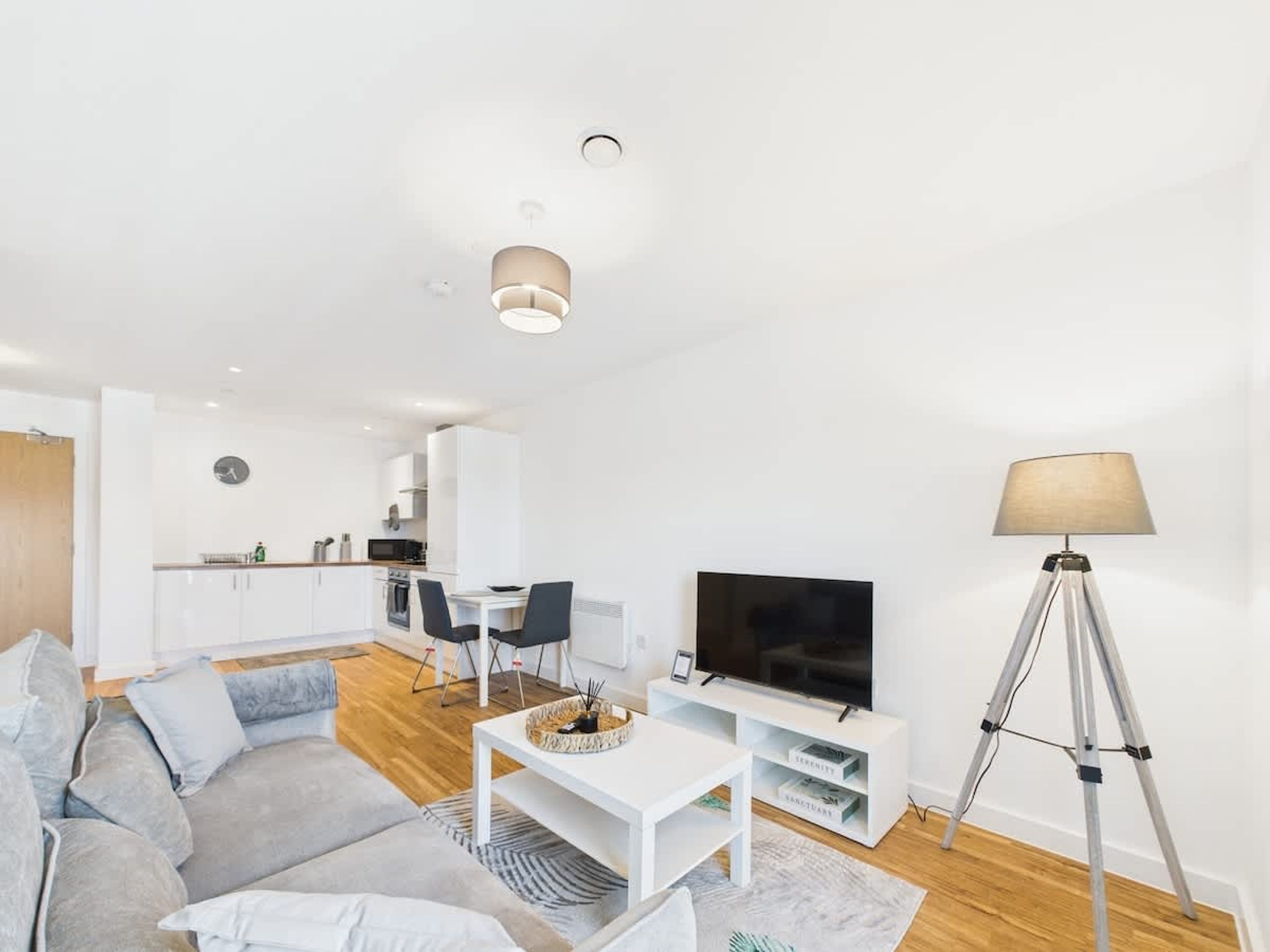 Una sala de estar moderna con un sofá, una mesa de centro, un televisor y una lámpara.