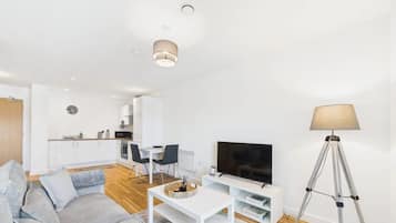 Una sala de estar moderna con un sofá, una mesa de centro, un televisor y una lámpara.