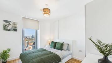 Un dormitorio moderno con cama, vistas a la ciudad, una lámpara de techo y una planta.