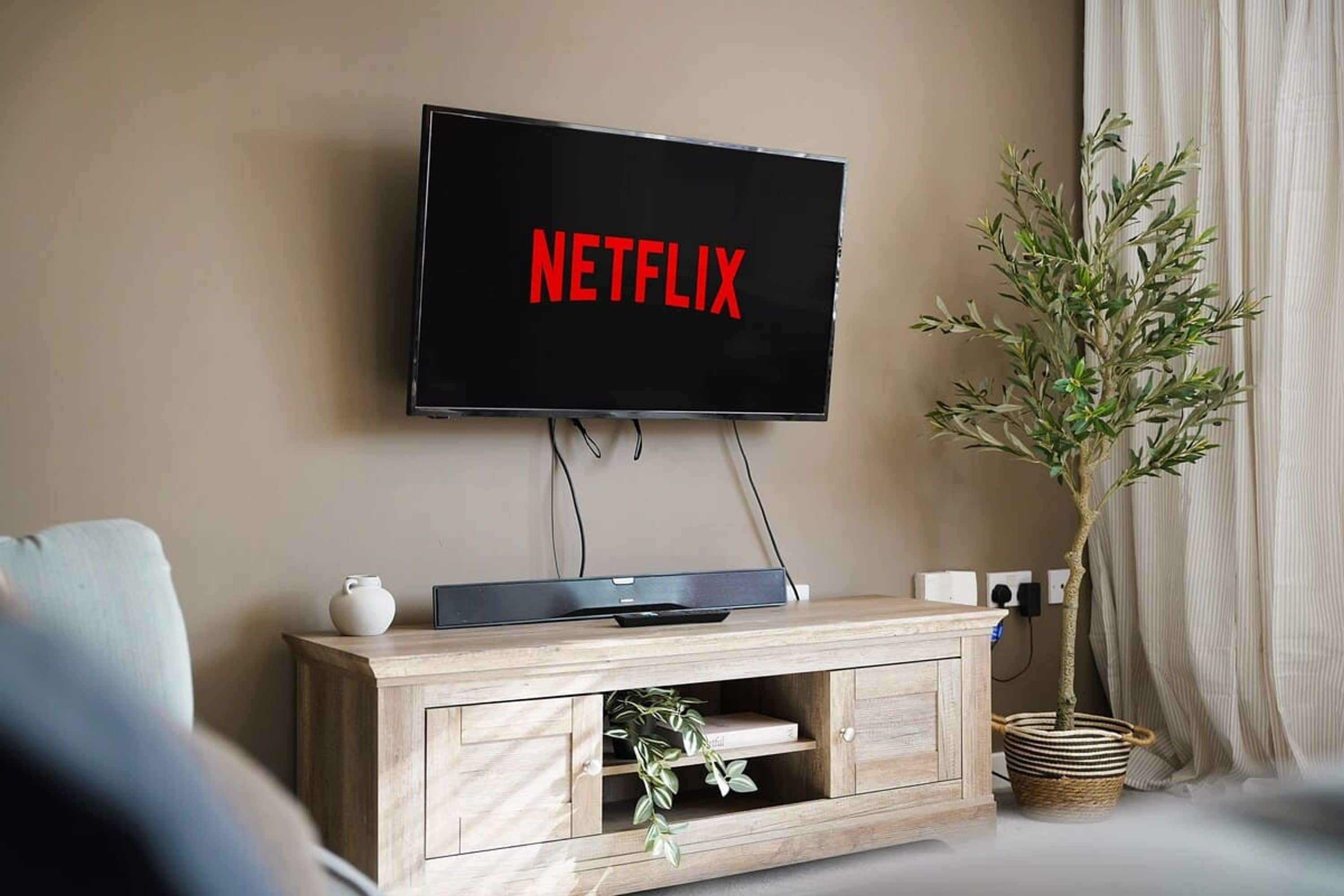 Ein an der Wand befestigter Fernseher, auf dessen Bildschirm 'NETFLIX' angezeigt wird.