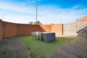 A backyard with a brick wall, a grassy area, and a wooden fence. - 3 Bedroom With Parking Close to Town Centre (Redcar)