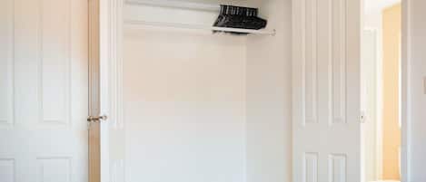A bedroom with a bed, a dresser, and a closet with a hanging rack.