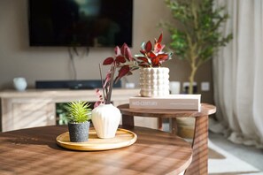 A round wooden table with a potted plant, a book titled 'MID-CENTURY,' and a small white vase with a plant. - 3 Bedroom With Parking Close to Town Centre (Redcar)