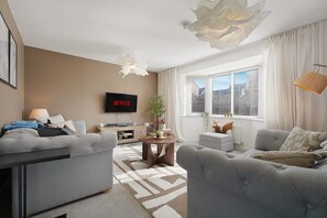 A modern living room with a grey sofa, a coffee table, and a TV mounted on the wall. - 3 Bedroom With Parking Close to Town Centre (Redcar)
