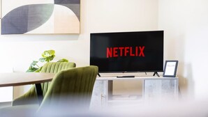A modern living room with a flat-screen TV displaying the Netflix logo, a green armchair, a small table, and a plant. - Central 2bed With Easy Access to Local Attractions (Barnard Castle)