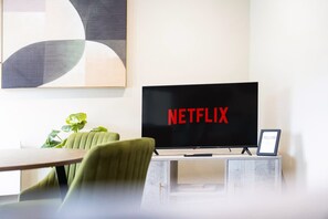 A modern living room with a flat-screen TV displaying the Netflix logo, a green armchair, a small table, and a plant. - Central 2bed With Easy Access to Local Attractions (Barnard Castle)