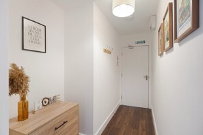 A hallway with a wooden floor, a white door, and a wall-mounted sign. - Central 2bed With Easy Access to Local Attractions (Barnard Castle)