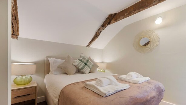 A bedroom with a bed, pillows, a bedside table with a lamp, and a mirror on the wall. - Central 2bed With Easy Access to Local Attractions (Barnard Castle)