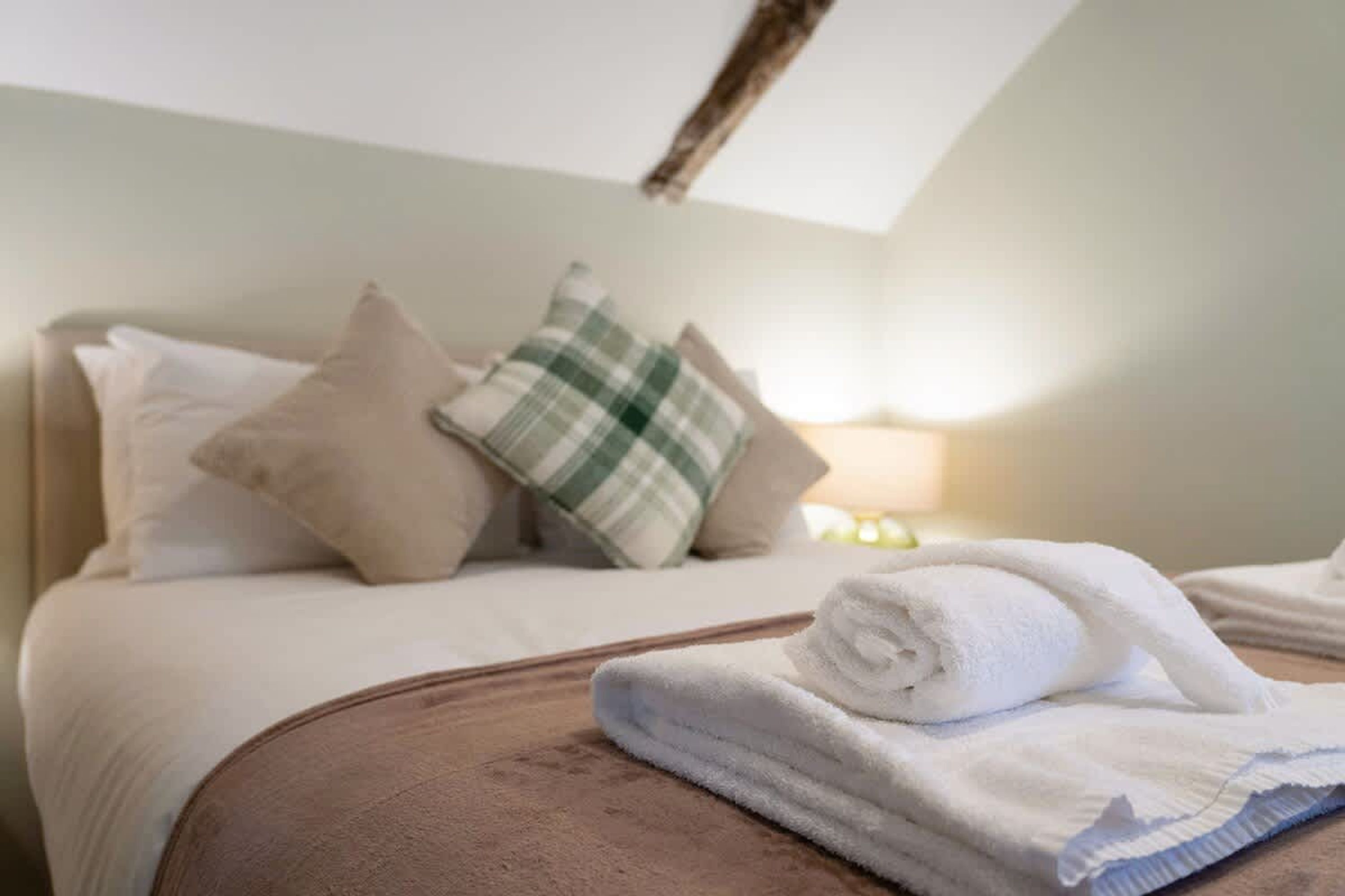A neatly made bed with pillows and a folded towel on a headboard.