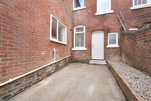 A narrow alleyway with a red brick building, a white door, and a small window. - Beachside 4BR Seaham Home by Stay With Us (Seaham)