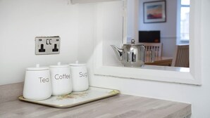 A kitchen counter with three white containers labeled 'Tea,' 'Coffee,' and 'Sugar,' and a silver teapot on a windowsill. - 3 Bedroom in Haughton Road With Free Wifi (Darlington)