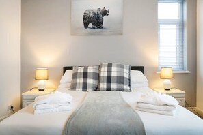 A neatly made bed with a gray blanket, two pillows with a checkered pattern, and two bedside lamps on either side. - 3 Bedroom in Haughton Road With Free Wifi (Darlington)