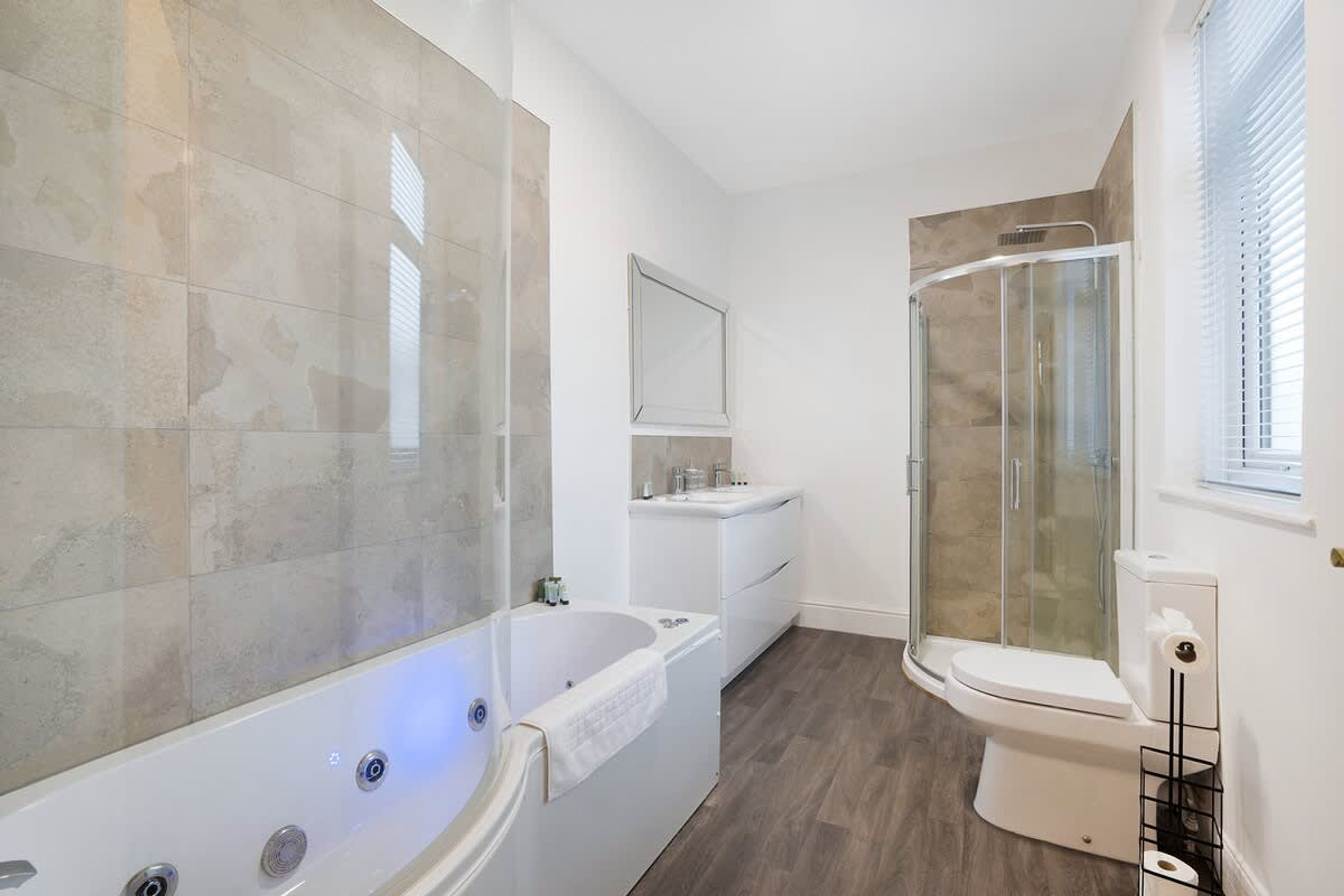 Un baño moderno con bañera, cabina de ducha y retrete.