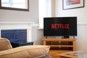 Uma sala de estar com uma televisão em um suporte de madeira exibindo o logotipo da Netflix.
