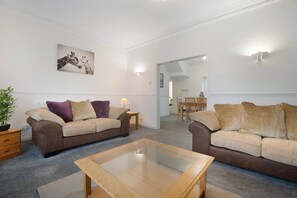 A living room with two sofas, a glass coffee table, and a painting on the wall. - 3 Bedroom in Haughton Road With Free Wifi (Darlington)