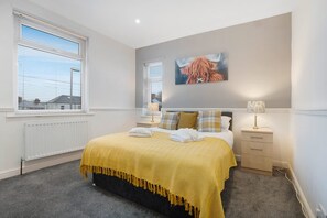 A bedroom with a bed, a nightstand, a lamp, and a painting on the wall. - 3 Bedroom in Haughton Road With Free Wifi (Darlington)