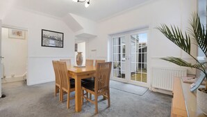 A dining area with a wooden table and chairs, a vase, and a framed picture on the wall. - 3 Bedroom in Haughton Road With Free Wifi (Darlington)