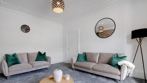 A modern living room with two sofas, a coffee table, a floor lamp, and a mirror on the wall. - 4BR South Shields Stay Sleeps 8 by Stay With Us (South Shields)