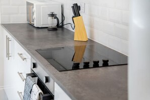 A kitchen with a modern stove, a coffee maker, and a knife block. - 4BR South Shields Stay Sleeps 8 by Stay With Us (South Shields)