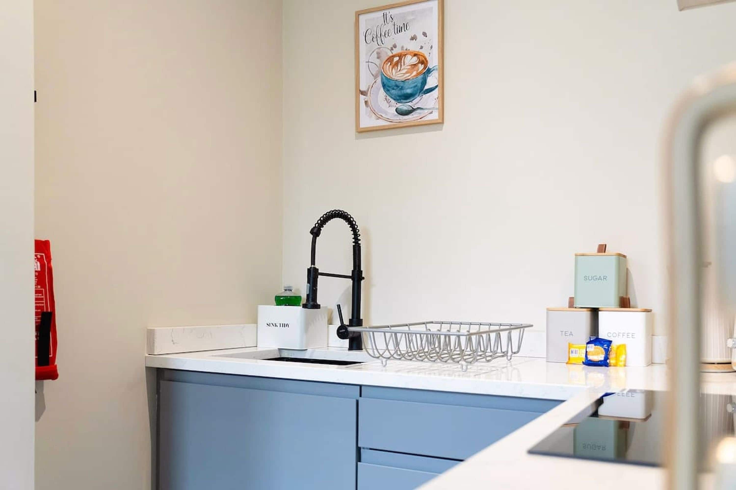 A kitchen with a sink, a coffee machine, and a tea and coffee box.
