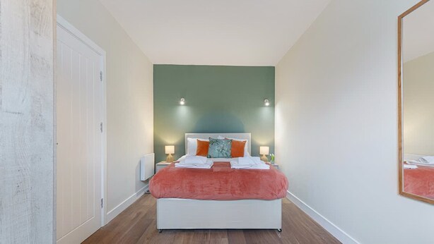 A bedroom with a bed, bedside tables, and a mirror. - Stylish 1-bed Stay in the Heart of Barnard Castle (Barnard Castle)